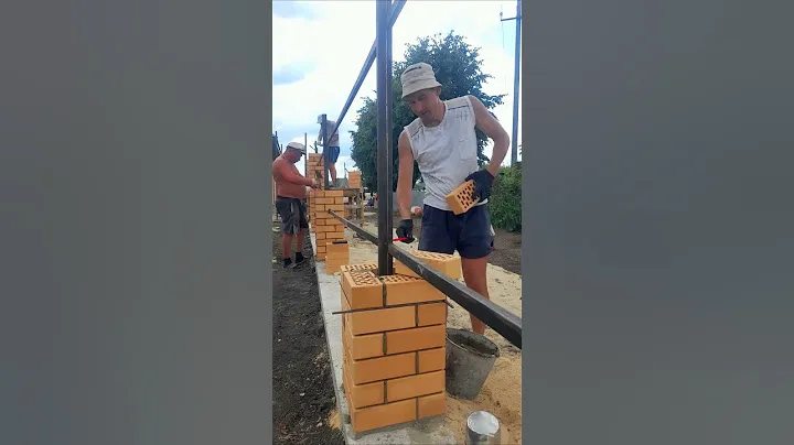 Каменщики кладут кирпичные столбы для забора. Fence construction